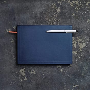 Blank closed notepad and pen on concrete background. Branding mock up. Top view.
