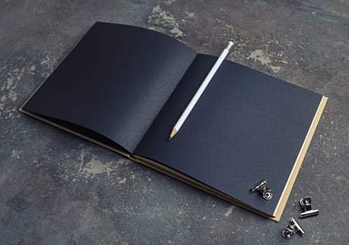 Blank black paper sketchbook, pencil and metal clips. Branding mock up.