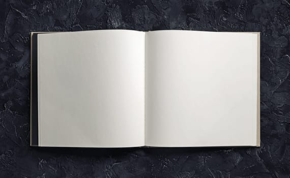 Blank open book or brochure on black plaster background. Mock-up for graphic designers portfolios. Responsive design mockup.
