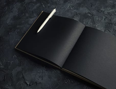 Blank black open brochure or notebook and pen. Responsive design mockup.