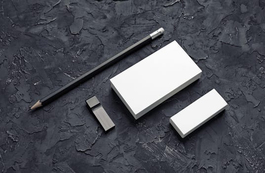 Brand identity mockup. Blank business card, pencil, eraser and usb flash drive on black plaster background.