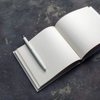 Photo of blank sketchbook and pen on concrete background. Responsive design mockup. Stationery elements.