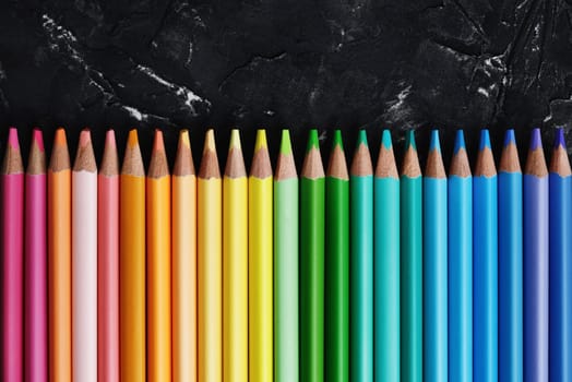 Color pencils for drawing on black plaster background. Top view.