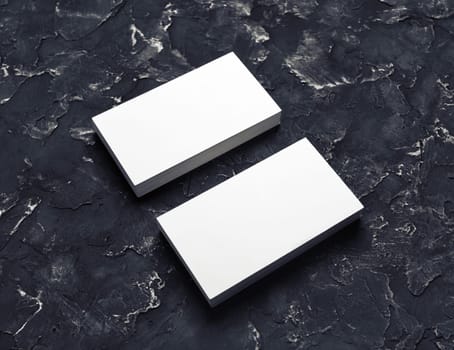 Photo of blank business cards on black plaster background. Mock-up for branding identity for designers.