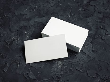 Photo of blank business cards on black plaster background. Template for your design.