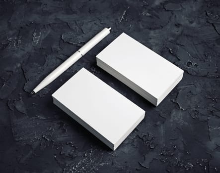 Blank stationery set. Photo of blank business cards and pen on black plaster background.