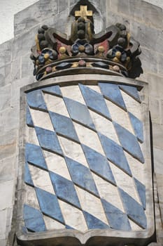 The Bavarian coat of arms with its blue and white rhombuses and crown in the Free State of Bavaria on a wall.