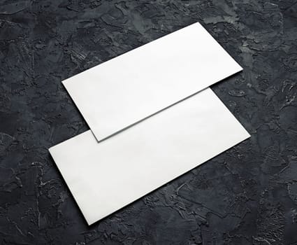 Two blank envelopes on black plaster background. Template for branding identity.