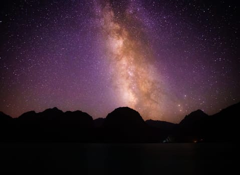 Night sky with prominent view of Milky Way over the lake Iskanderkul in the mountains of Tajikistan