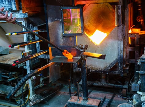 Shaping the hot glass gather during glassblowing process