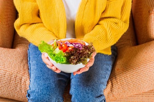 Female hands holding bowl with green lettuce salad on legs, Above front woman eating fresh salad meal vegetarian spinach in a bowl, Clean detox healthy homemade food concept