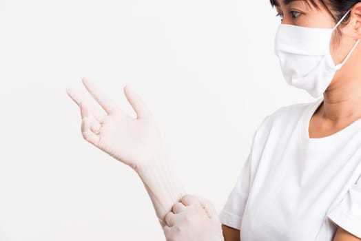 Woman wearing and putting hand to white rubber latex surgical medical glove for doctor and fave mask protect, studio shot isolated on white background, Hospital medical infection control concept
