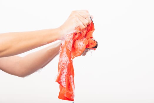 Closeup young Asian woman use hands washing color clothes with detergent have soapy bubble water, studio shot isolated on white background, laundry concept