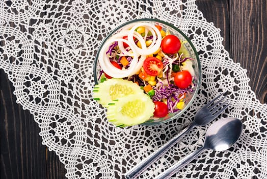 Top view of the healthy colorful fresh salad bowl with quinoa, tomatoes, and mixed greens vegetable in a dish on black wooden background, Health snack food