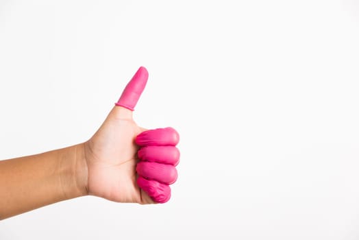 Woman hand wearing pink finger cots rubber protect help prevent fingerprints on the finger touched piece with thumb up sign gesturing, studio shot isolated on white background