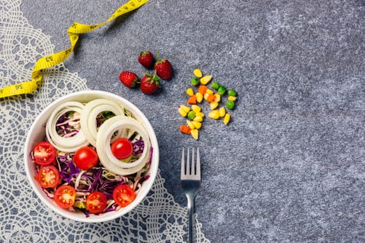 Top view of the healthy colorful salad bowl with tomatoes fresh mixed greens vegetable in a dish and measuring tape on cement background, Health salad snack diet food weight loss concept