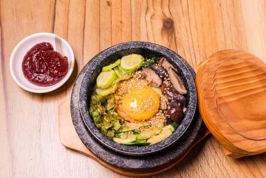 Bibimbap in a black heated stone bowl, Korean traditional dish- bibimbap mixed rice with vegetables Include beef and fried egg, Japanese hot pot food