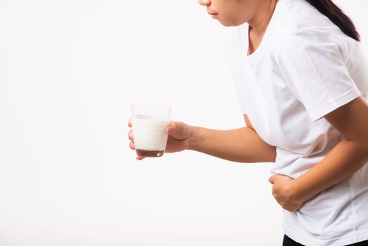 Closeup young woman intolerant use hand holding glass milk she is bad stomach ache she has bad lactose intolerance unhealthy problem with dairy food products, studio shot isolated on white background