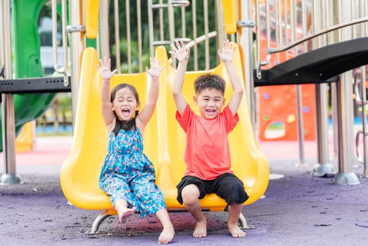 Asian child smiling playing on slider bar toy outdoor playground, happy preschool little kid having funny while playing on the playground equipment in the daytime in summer, Little girl & boy climbing