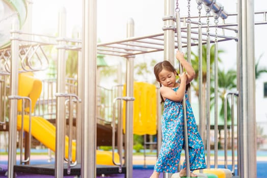 Asian child playing on outdoor playground, happy preschool little kid having funny while playing on the playground equipment in the daytime in summer, Outside education, Little girl climbing