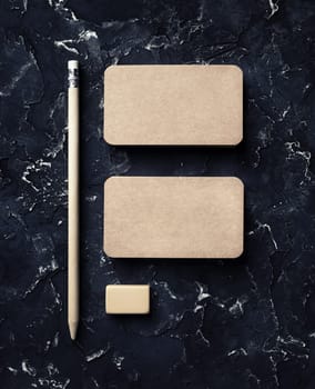 Blank vintage business cards, pencil and eraser on black plaster background. Brand ID mockup. Top view.