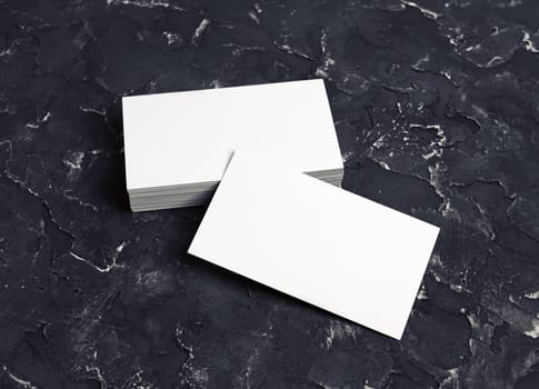 Several blank business cards on black plaster background. Mock-up for branding id.