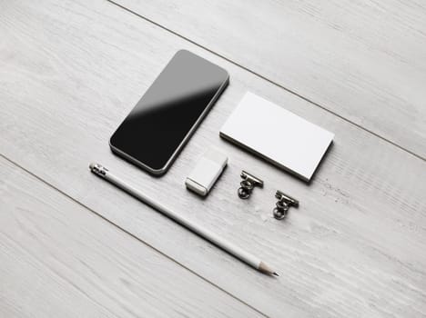 Branding stationery template. Blank business cards, smartphone, pencil, eraser and clips on light wooden background. ID mockup.