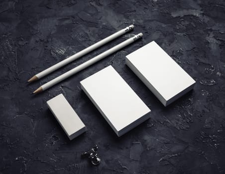 Blank branding identity. Blank business card, pencils and eraser on black plaster background.