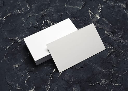 Photo of blank white business cards on black plaster background. Mock-up for branding identity. Blank template for design presentations and portfolios.