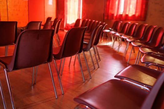 Many chairs in a room for an event with red ambiance