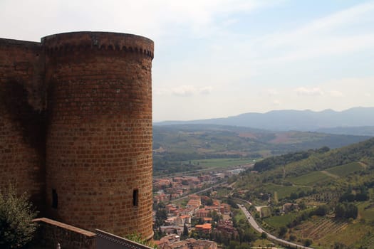 Stone tower and green hills with rooftops near Orvieto in the center of Italy