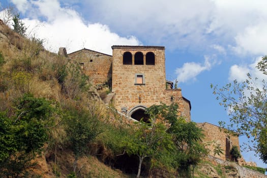 A traditional rock house on the cliff of a mountain with olive trees in Umbria in Italy
