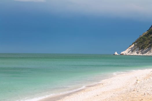 Dramatic sky above the turquoise Adriatic Sea and the white rocks in Portonovo on Conero in Italy