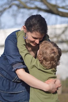Happy mother holding little child in her arms with love in a garden outdoors in summertime