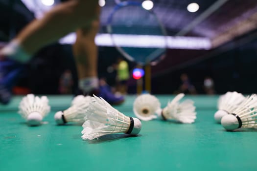 shuttlecock on green badminton playing court with player in background