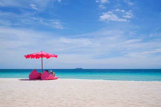 Pink parasol and  seat on the tropical beach, Vacation background.,Idyllic beach