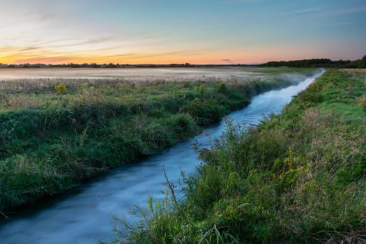 A small river and fog in the meadow, summer view, Czulczyce, Poland
