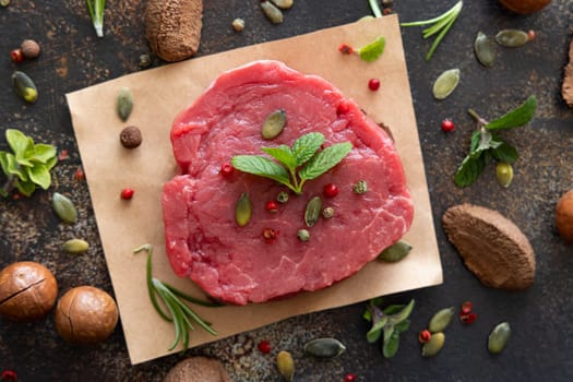 Raw beef fillet steaks on dark table top view. Portioned filet mignon with spices and herbs. Concept of summer food.