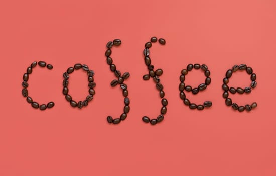 Text COFFEE made of Roasted Coffee beans top view on pink background. Represent breakfast, love, energy, freshness or aroma