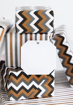 Present with blank gift tag close up. Gift boxes wrapped in Striped and chevron geometric paper. Christmas, New Year, Birthday, Anniversary label mockup
