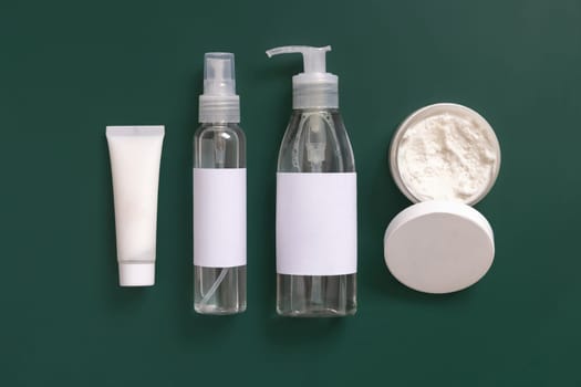 Homemade Cosmetics in plastic tubes and bottles on dark green top view. Brand packaging mockup. Organic natural cosmetics for skin and hair care
