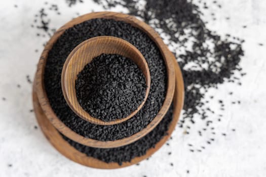 Indian spice Black cumin (nigella sativa or kalonji) seeds in wooden bowls top view with copy space. Traditional medicine, healthy and vegetarian food concept.