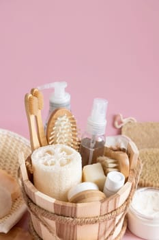 Sauna bucket with organic natural cosmetics and zero waste reusable accessories for skin and hair care on pink. Close up of eco friendly beauty products for bath, massage or spa salon