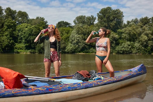 Girls standing by a canoe drinking beer in summer
