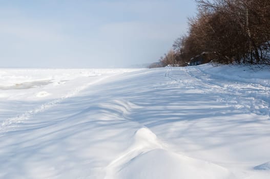 Stunning view of the frozen river covered with chunks of ice and white frosted snow. Snowy desert. The river breaks through the ice.