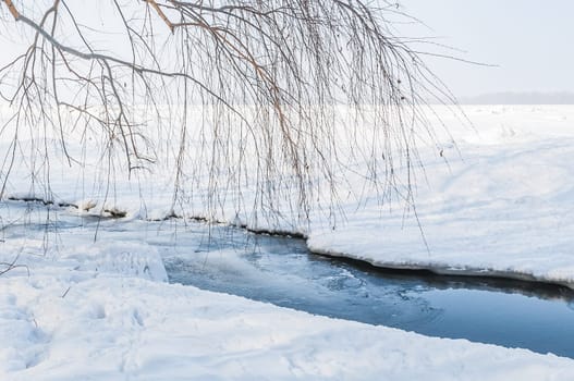 Stunning view of the frozen river covered with chunks of ice and white frosted snow. Snowy desert. The river breaks through the ice.
