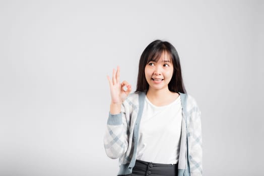 Woman smiling showing made finger OK symbol sign to agree studio shot isolated white background, Happy Asian portrait beautiful young female lifestyle agree hand sign with copy space