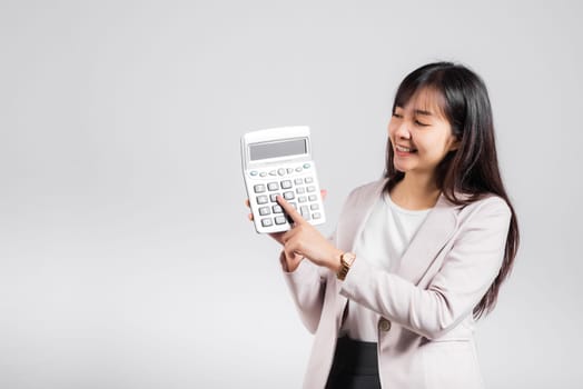 Tax day concept. Woman confident smiling holding calculator and finger point device, Portrait excited happy Asian female studio shot isolated on white background, Account and finance counting income