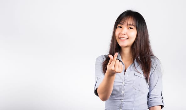 Woman standing her smile confidence showing mini heart sign with her finger isolated white background, Asian happy portrait beautiful young female send love and happy valentine in studio shot