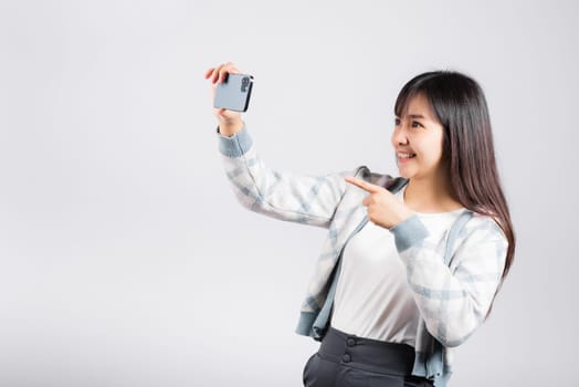 Woman excited holding smartphone to shooting selfie photo front camera studio shot isolated white background, happy young female smiling taking photography by mobile phone on mobile phone